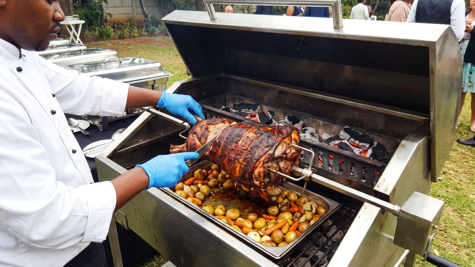 A chef in gloves carving meat off a whole lamb on the spit braai machine at a buffet