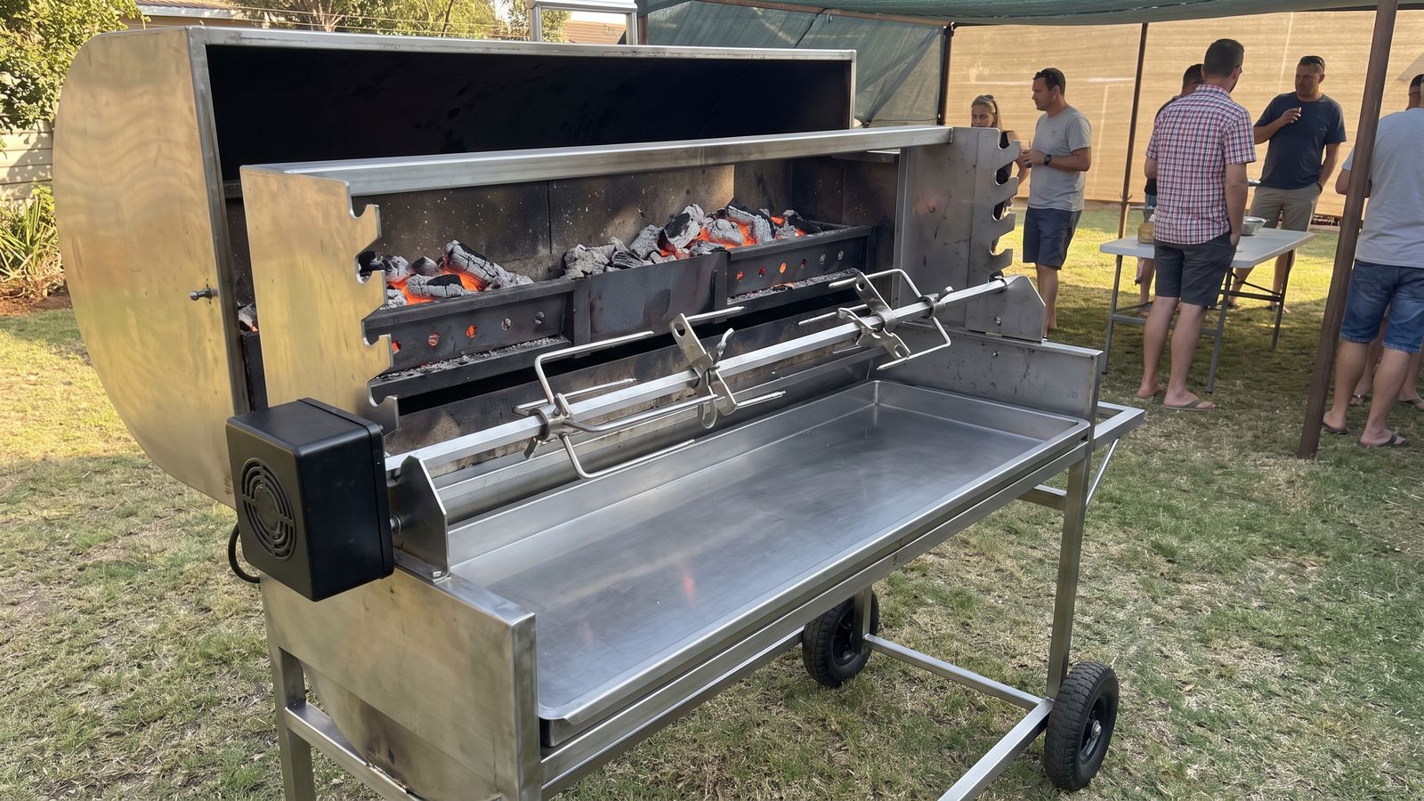 Spit braai machine: an empty charcoal machine with the lid open, spit rod, spine clamps, motor and coal channels