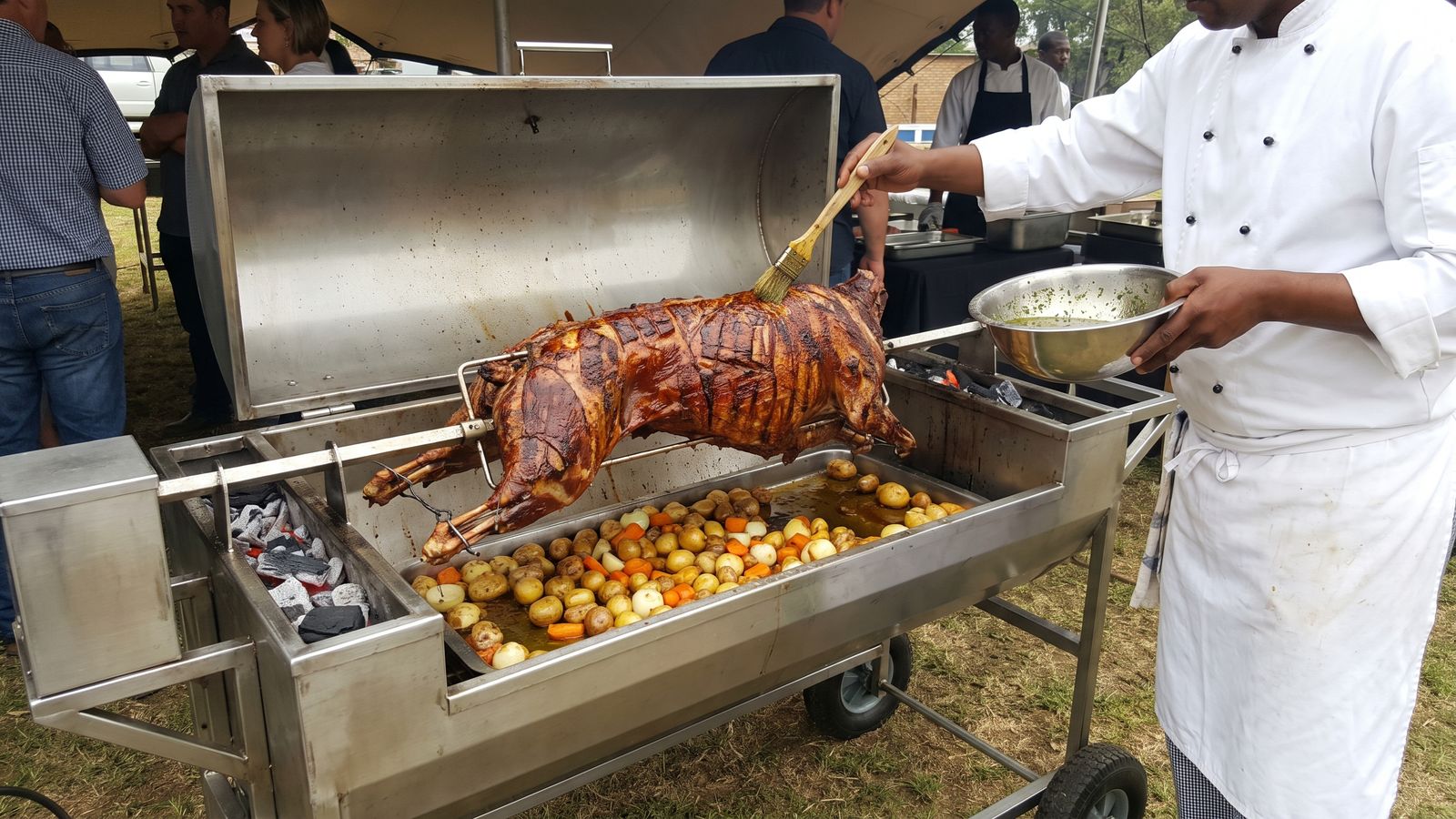 Spit braai marinade: a chef basting a whole lamb on the spit from a bowl of garlic, lemon and rosemary baste