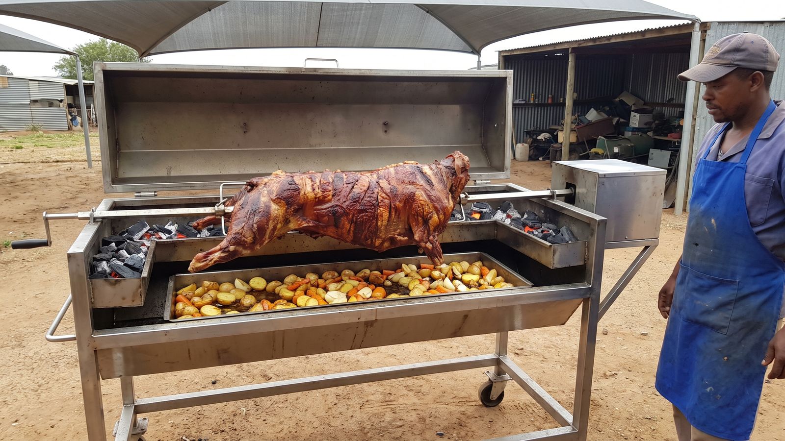 Whole lamb spit braai on a stainless machine in a farmyard under shade netting, the set-up Spit Braai Feast uses in Worcester