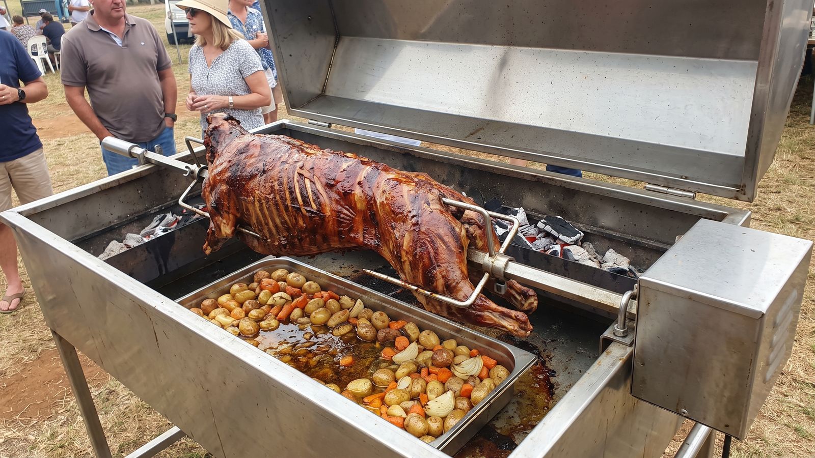 What is a spit braai: a whole lamb turning on a rod over coals with roast potatoes in the tray below